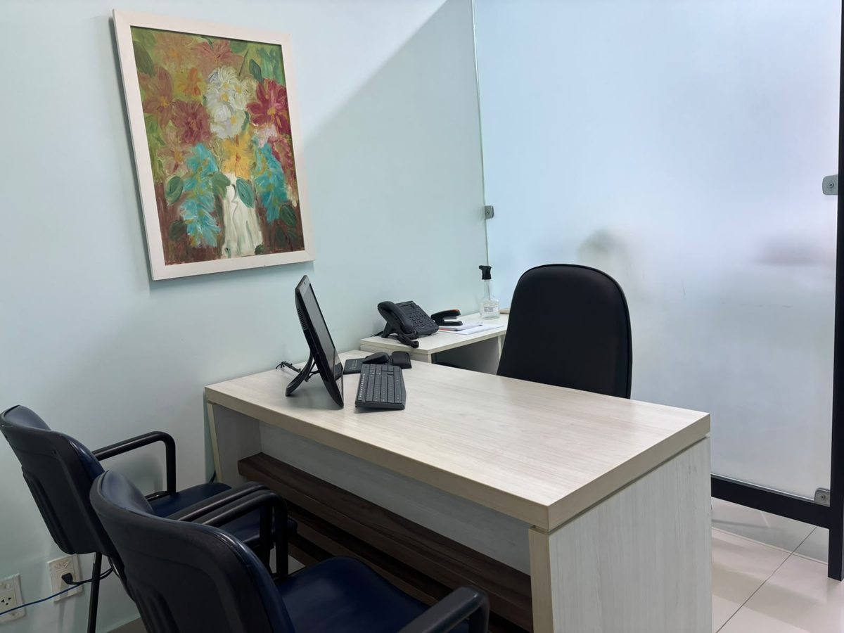 Consultório da Clínica Guri, com mesa, cadeiras para o acompanhante e divisória de vidro fosco